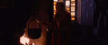 Movie still from “Red Riding Hood” (2011), directed by Catherine Hardwicke – A woman in a red dress is cooking in a kitchen; Medium shot, Low angle