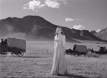 Movie still from “Red River” (1948), directed by Howard Hawks – A black and white photo of a woman standing in the middle of a field; Wide shot, Low angle
