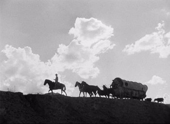 Movie still from “Red River” (1948), directed by Howard Hawks – A black and white photo of a man on a horse drawn carriage; Extreme Wide shot, Low angle
