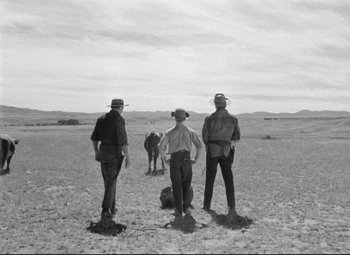 Movie still from “Red River” (1948), directed by Howard Hawks – A group of men standing on top of a dry grass field; Extreme Wide shot, Over the shoulder angle