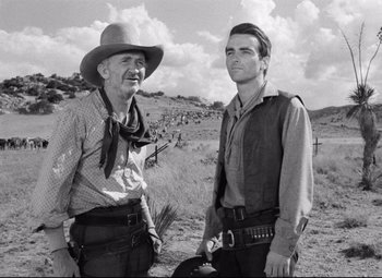 Movie still from “Red River” (1948), directed by Howard Hawks – A man and a man standing next to each other in a field; Medium shot, Low angle