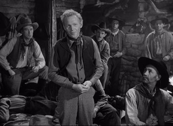 Movie still from “Red River” (1948), directed by Howard Hawks – A group of men sitting in front of a stone wall; Medium shot, Over the shoulder angle