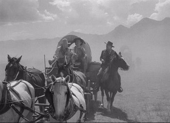 Movie still from “Red River” (1948), directed by Howard Hawks – A black - and - white photo of a covered wagon and two men on horses; Wide shot, Low angle
