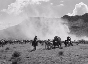 Movie still from “Red River” (1948), directed by Howard Hawks – A black and white photo of a wagon train in the wild west; Extreme Wide shot, Low angle