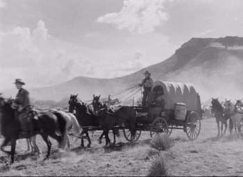 Movie still from “Red River” (1948), directed by Howard Hawks – An old photo of a man riding a wagon pulled by horses; Extreme Wide shot, Low angle