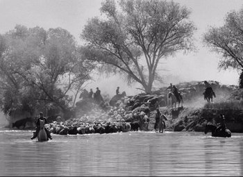 Movie still from “Red River” (1948), directed by Howard Hawks – A group of people riding horses across a river; Extreme Wide shot, High angle