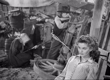 Movie still from “Red River” (1948), directed by Howard Hawks – An old black and white photo of a woman holding an arrow; Medium shot, High angle