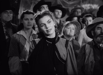 Movie still from “Red River” (1948), directed by Howard Hawks – A woman standing in front of a group of people; Medium shot, Over the shoulder angle
