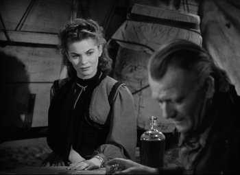 Movie still from “Red River” (1948), directed by Howard Hawks – A woman sitting at a table next to an older man; Medium shot, Over the shoulder angle