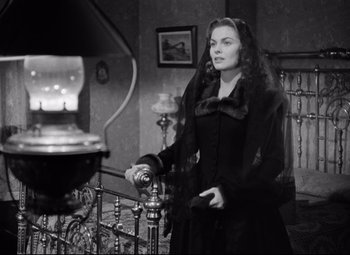 Movie still from “Red River” (1948), directed by Howard Hawks – An old photo of a woman standing on a stair railing; Medium shot, High angle