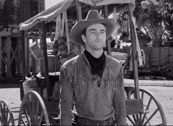 Movie still from “Red River” (1948), directed by Howard Hawks – A man wearing a cowboy hat standing in front of a horse drawn carriage; Medium shot, Low angle