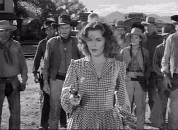 Movie still from “Red River” (1948), directed by Howard Hawks – An old photo of a woman holding a gun in front of a crowd; Medium shot, Low angle