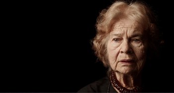 An older woman wearing a black shirt and a red necklace