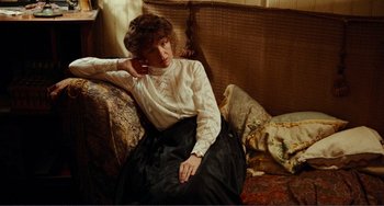 Movie still from “Reds” (1981), directed by Warren Beatty – A woman sitting on a couch wearing a white shirt; Medium shot, High angle