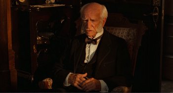 Movie still from “Reds” (1981), directed by Warren Beatty – An old man sitting in a chair wearing a bow tie; Close Up shot, High angle