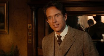 Movie still from “Reds” (1981), directed by Warren Beatty – A man wearing a suit and tie in front of a wooden wall; Close Up shot, Over the shoulder angle