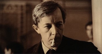 Movie still from “Reds” (1981), directed by Warren Beatty – An older man in a suit and tie smoking a cigarette; Close Up shot, Low angle