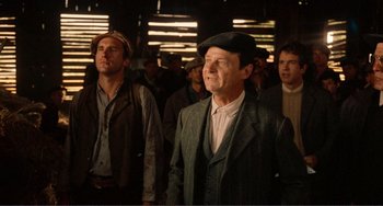 Movie still from “Reds” (1981), directed by Warren Beatty – A group of men standing next to each other in a room; Medium shot, Over the shoulder angle