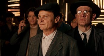 Movie still from “Reds” (1981), directed by Warren Beatty – A group of men standing next to each other wearing hats; Medium shot, Low angle