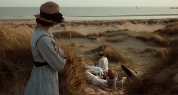 Movie still from “Reds” (1981), directed by Warren Beatty – A group of people sitting on the beach near the water; Wide shot, High angle