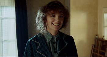 A woman smiling for the camera in a blue jacket