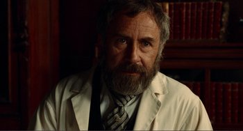 Movie still from “Reds” (1981), directed by Warren Beatty – An older man wearing a white lab coat and a tie; Close Up shot, Over the shoulder angle