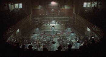 Movie still from “Reds” (1981), directed by Warren Beatty – An overhead view of an audience in an auditorium; Extreme Wide shot, High angle
