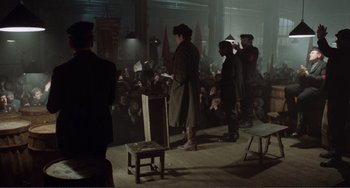 Movie still from “Reds” (1981), directed by Warren Beatty – A group of men standing in front of an audience; Wide shot, High angle