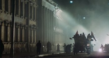 Movie still from “Reds” (1981), directed by Warren Beatty – A group of people standing in front of a large building at night; Extreme Wide shot, Low angle