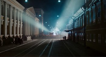 Movie still from “Reds” (1981), directed by Warren Beatty – People are walking down the street at night in the dark; Extreme Wide shot, High angle