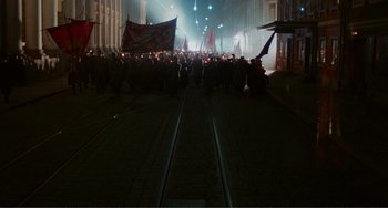 Movie still from “Reds” (1981), directed by Warren Beatty – A group of people walking down a street at night; Extreme Wide shot, High angle