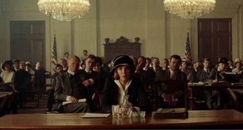 Movie still from “Reds” (1981), directed by Warren Beatty – A group of people sitting at a table in front of a crowd; Wide shot, Low angle