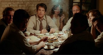 Movie still from “Reds” (1981), directed by Warren Beatty – A group of people sitting at a table with food; Medium shot, High angle