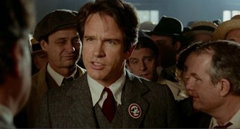 Movie still from “Reds” (1981), directed by Warren Beatty – A man in a suit and tie standing next to a crowd; Close Up shot, Over the shoulder angle