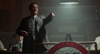 Movie still from “Reds” (1981), directed by Warren Beatty – A man in a suit and tie pointing to the sky; Medium shot, Low angle