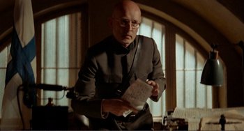 Movie still from “Reds” (1981), directed by Warren Beatty – A man in a suit and tie holding a piece of paper; Medium shot, Low angle