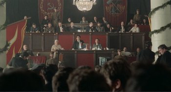 Movie still from “Reds” (1981), directed by Warren Beatty – A group of people sitting in a courtroom; Extreme Wide shot, High angle