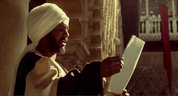 Movie still from “Reds” (1981), directed by Warren Beatty – A man wearing a white turban holding a piece of paper in his hands; Close Up shot, Low angle