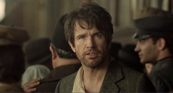 Movie still from “Reds” (1981), directed by Warren Beatty – A person wearing a suit and hat; Close Up shot, Over the shoulder angle