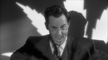 Movie still from “Reefer Madness: The Movie Musical” (2005), directed by Andy Fickman – A man in a suit and tie making a funny face; Close Up shot, Low angle