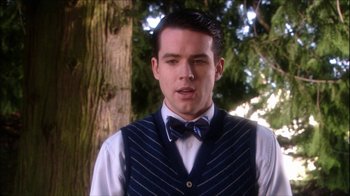 Movie still from “Reefer Madness: The Movie Musical” (2005), directed by Andy Fickman – A man in a vest and bow tie standing in front of a tree; Close Up shot, Over the shoulder angle