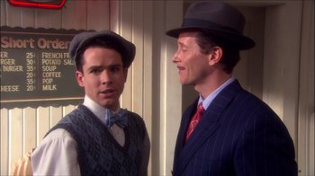 Movie still from “Reefer Madness: The Movie Musical” (2005), directed by Andy Fickman – A man in a suit and a man in a hat; Medium shot, Over the shoulder angle