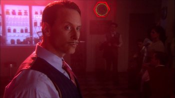 Movie still from “Reefer Madness: The Movie Musical” (2005), directed by Andy Fickman – A man in a suit and tie smoking a cigarette in a room; Close Up shot, Low angle