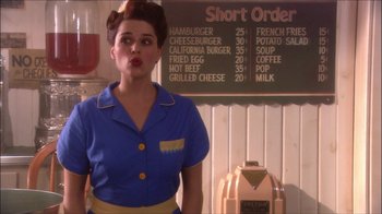 Movie still from “Reefer Madness: The Movie Musical” (2005), directed by Andy Fickman – A woman standing in front of a menu board; Medium shot, Over the shoulder angle