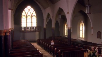 Movie still from “Reefer Madness: The Movie Musical” (2005), directed by Andy Fickman – A small child sitting in a pew in an empty church; Extreme Wide shot, High angle