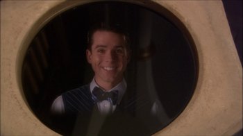 Movie still from “Reefer Madness: The Movie Musical” (2005), directed by Andy Fickman – A man in a vest and bow tie smiling; Close Up shot, Over the shoulder angle