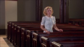 Movie still from “Reefer Madness: The Movie Musical” (2005), directed by Andy Fickman – A woman standing in front of wooden pedestals; Medium shot, Low angle