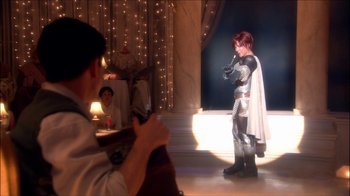 Movie still from “Reefer Madness: The Movie Musical” (2005), directed by Andy Fickman – A man in a suit of a medieval knight is standing in front of a woman; Wide shot, Over the shoulder angle