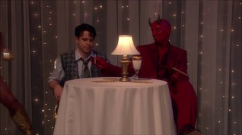 Movie still from “Reefer Madness: The Movie Musical” (2005), directed by Andy Fickman – Two men dressed up in costumes sitting at a table; Medium shot, High angle