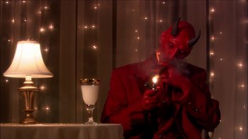 Movie still from “Reefer Madness: The Movie Musical” (2005), directed by Andy Fickman – A man dressed as a devil lighting a candle; Medium shot, High angle